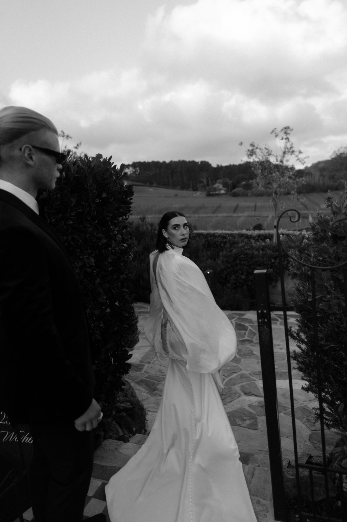 Bride glancing back over her shoulder at a garden gate