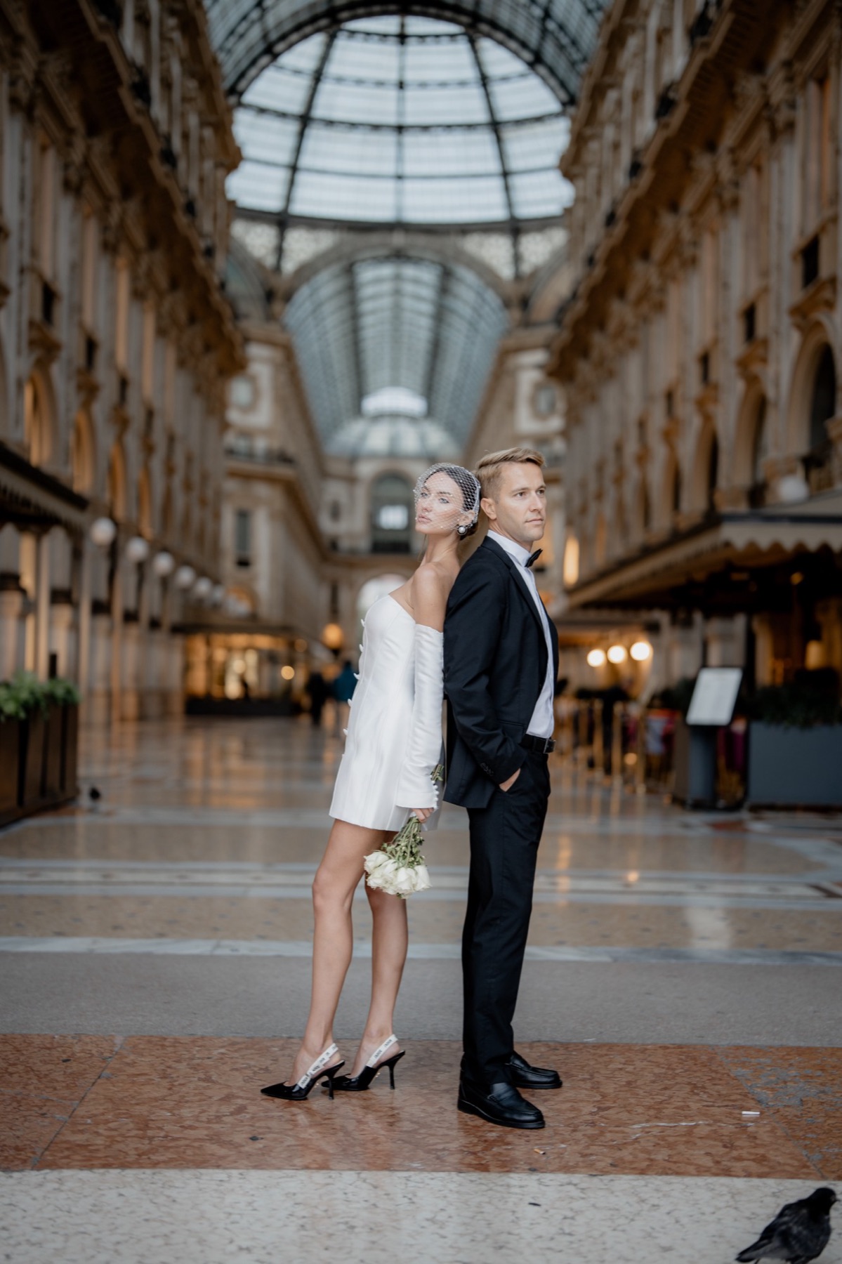 Couple standing back to back in Milan's Galleria Vittorio Emanuele II