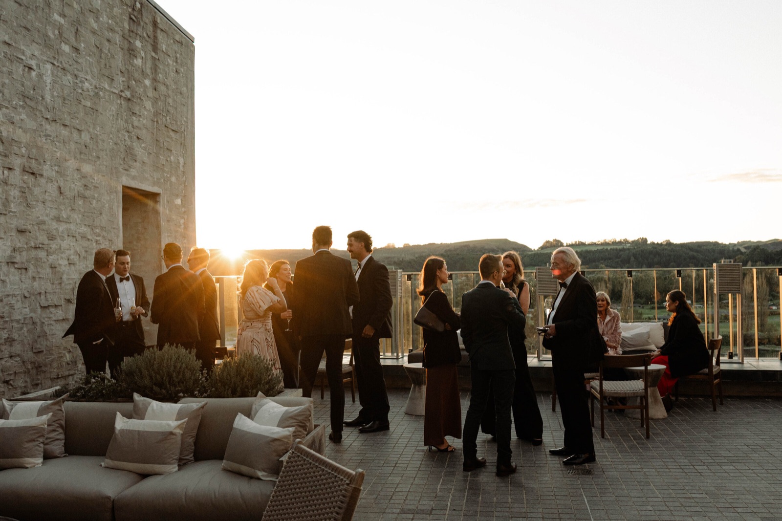 Wedding guests gathered on a stone terrace at sunset