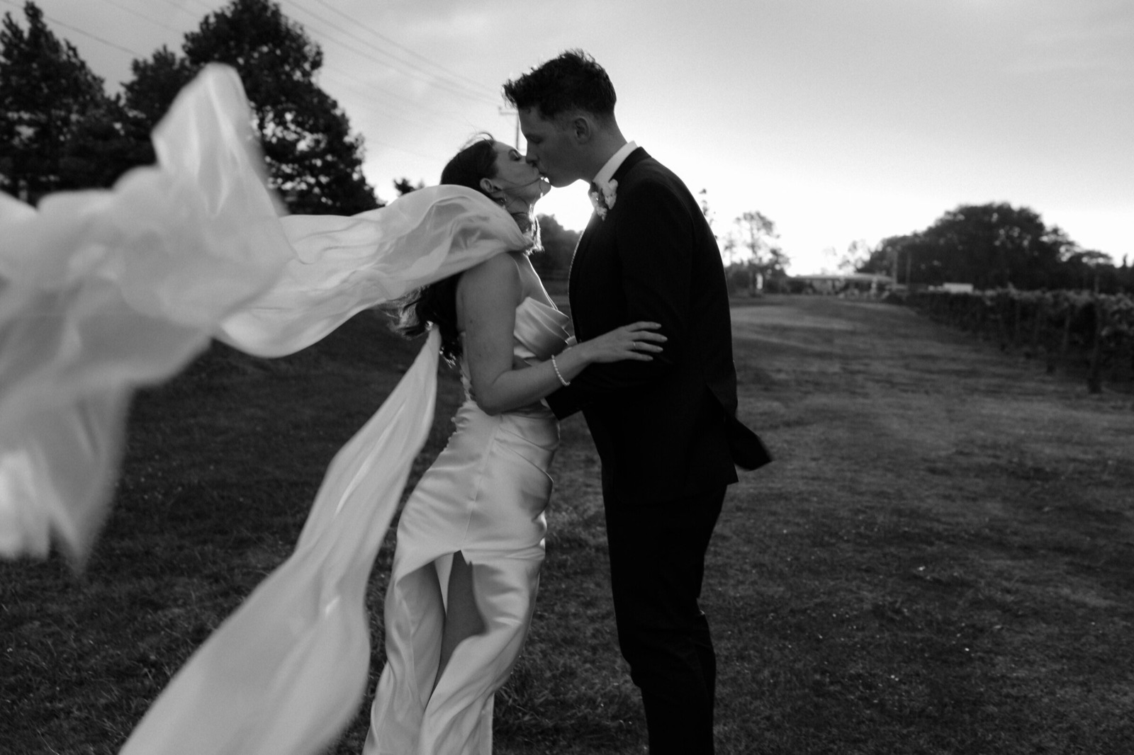 Couple kissing as her veil catches the wind