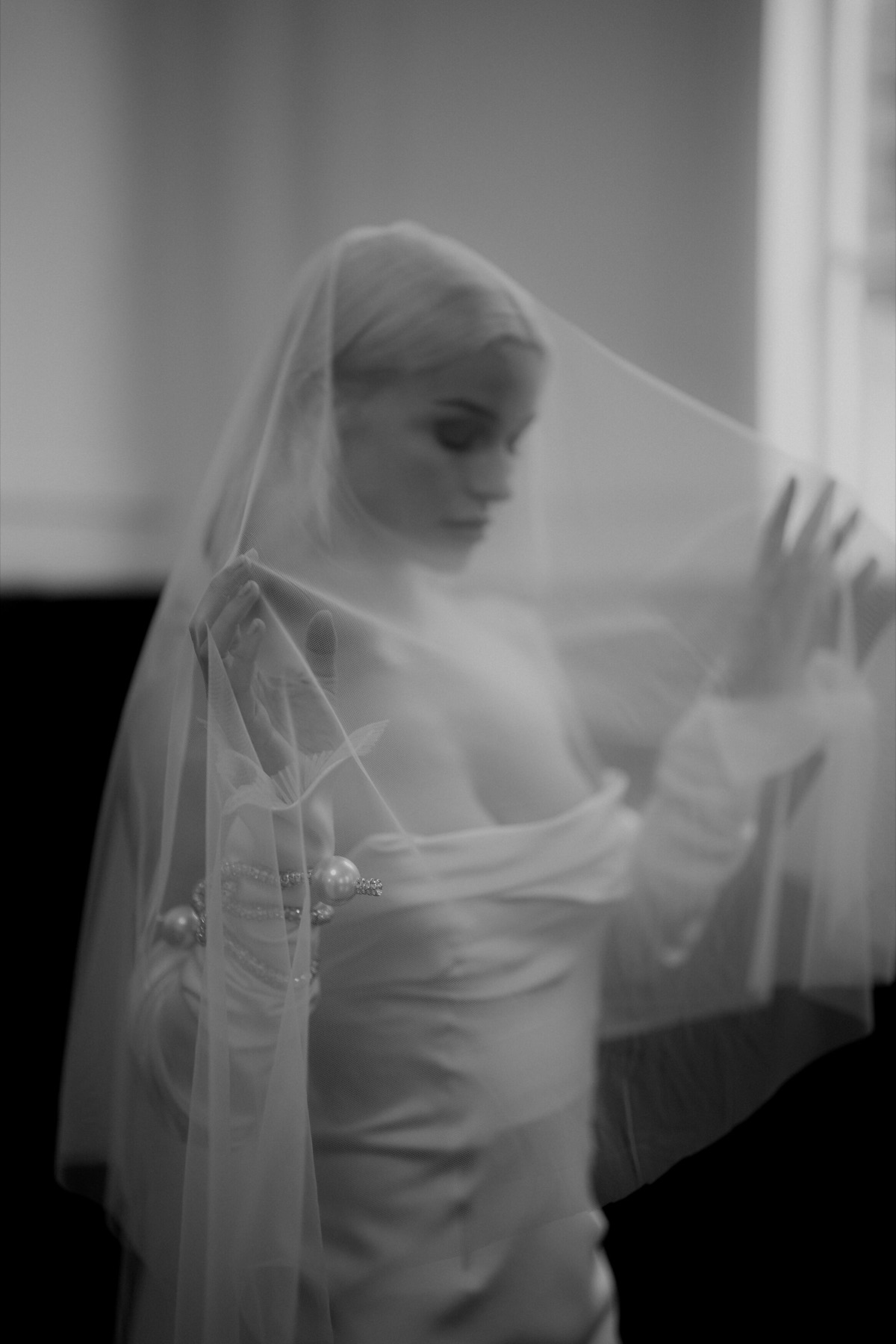 Bride lifting her veil in soft window light